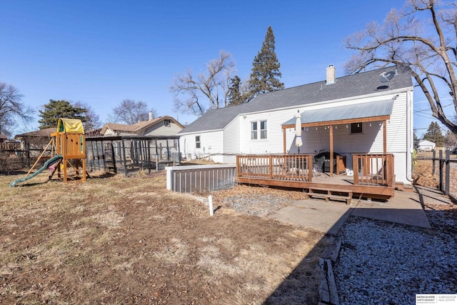 back of house with a playground and a deck