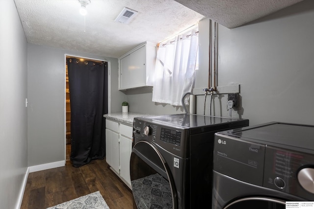 laundry room with cabinets, dark hardwood / wood-style floors, washing machine and dryer, and a textured ceiling