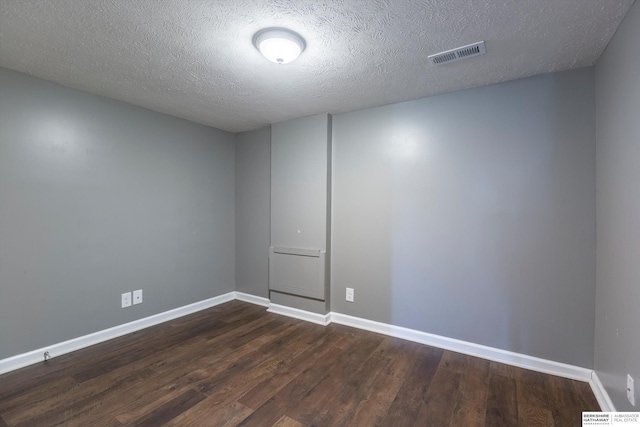 unfurnished room with a textured ceiling and dark hardwood / wood-style flooring