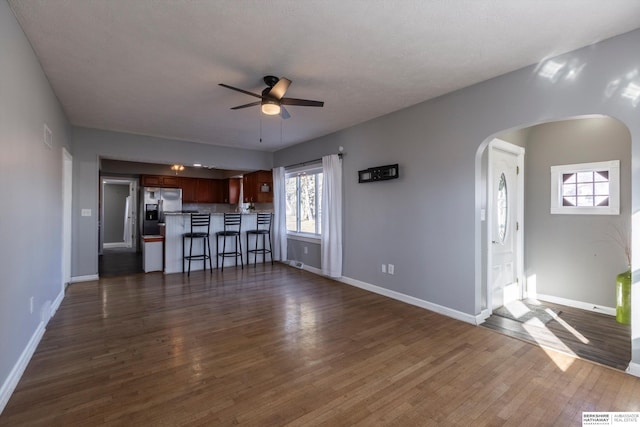 unfurnished living room featuring dark wood-type flooring and ceiling fan