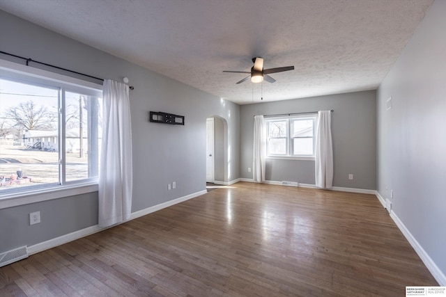 empty room with ceiling fan, wood-type flooring, and a textured ceiling