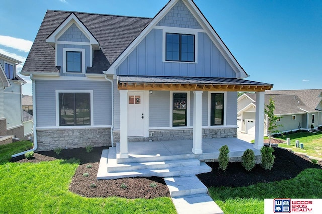 craftsman-style house featuring a garage, covered porch, and a front lawn