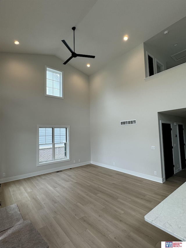 unfurnished living room featuring hardwood / wood-style flooring, ceiling fan, and high vaulted ceiling