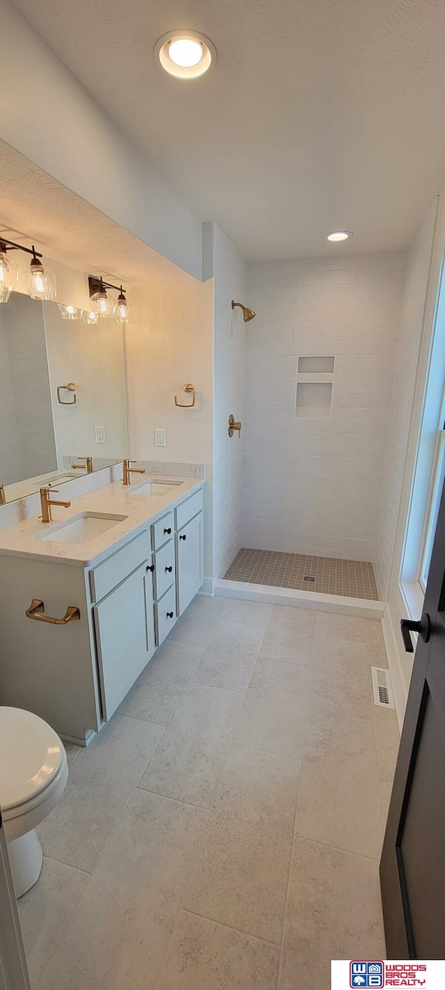 bathroom with vanity, a tile shower, and toilet