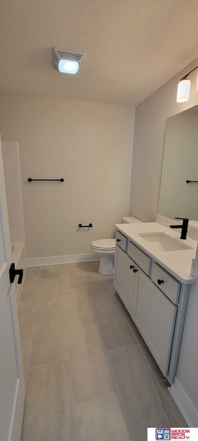 bathroom with vanity, a bath, a textured ceiling, tile patterned floors, and toilet