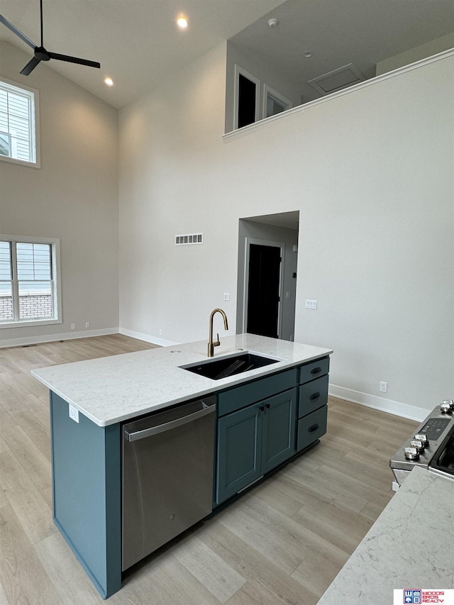 kitchen with a high ceiling, an island with sink, appliances with stainless steel finishes, and sink