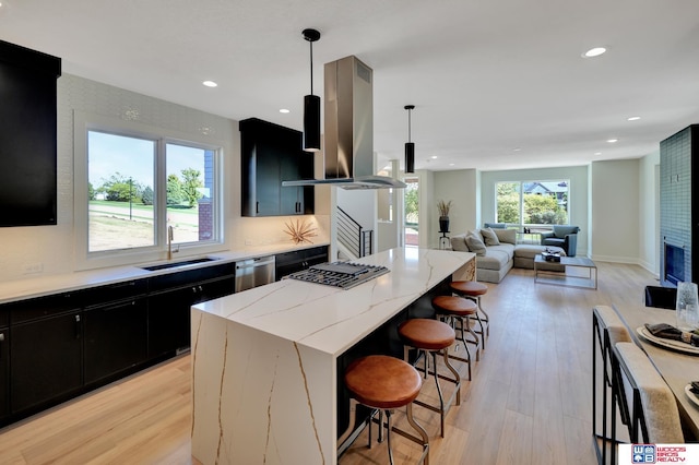 kitchen with sink, island range hood, decorative light fixtures, a kitchen island, and stainless steel appliances