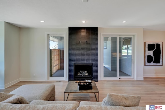 living room featuring a tile fireplace and light wood-type flooring