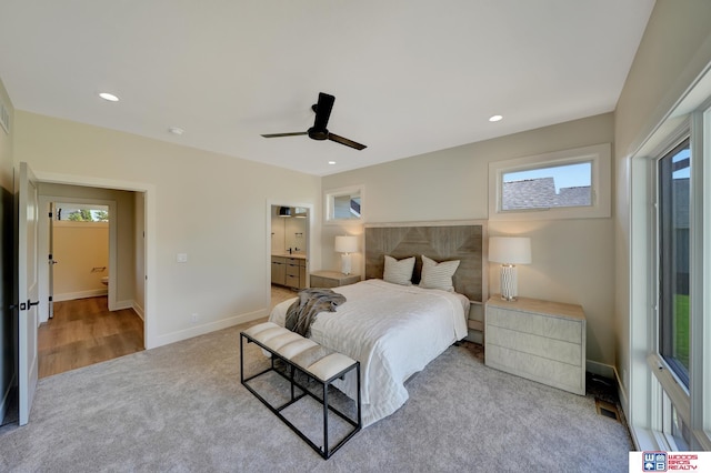 carpeted bedroom with ceiling fan, ensuite bath, and multiple windows