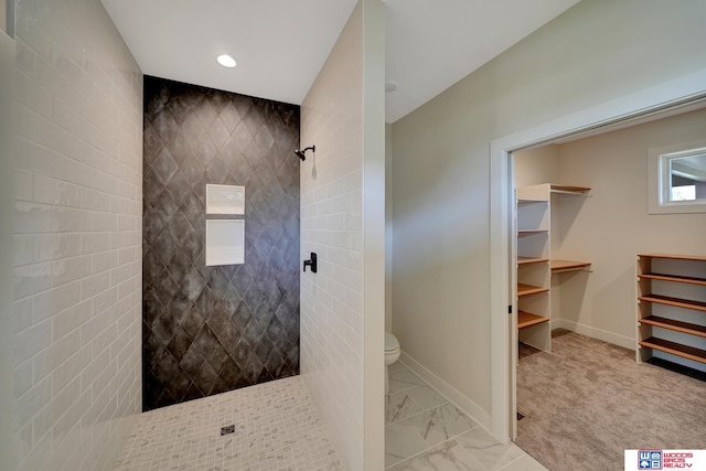 bathroom featuring a tile shower and toilet