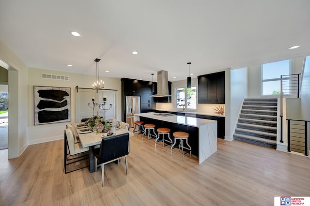 kitchen featuring hanging light fixtures, island exhaust hood, a center island, and stainless steel fridge