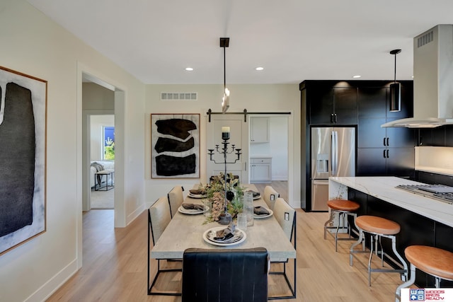 dining area with a barn door and light hardwood / wood-style floors