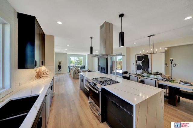 kitchen with gas range, decorative light fixtures, a center island, island exhaust hood, and light hardwood / wood-style floors