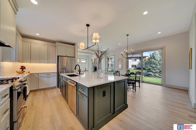 kitchen with light countertops, appliances with stainless steel finishes, a sink, and range hood