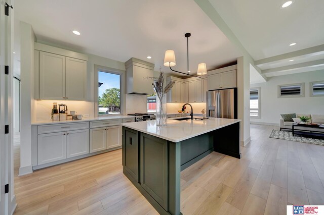 kitchen with appliances with stainless steel finishes, decorative light fixtures, light countertops, light wood-type flooring, and recessed lighting