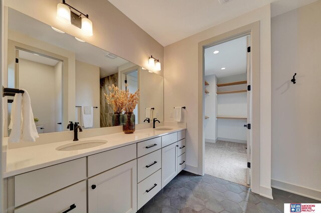 full bath featuring double vanity, a sink, and baseboards