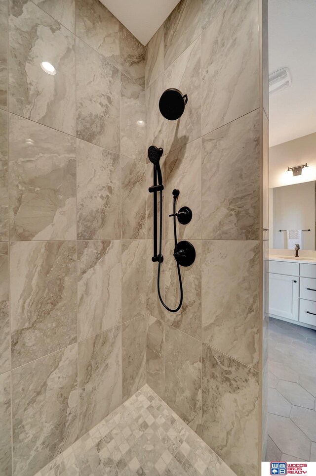 full bathroom featuring visible vents, a tile shower, and vanity