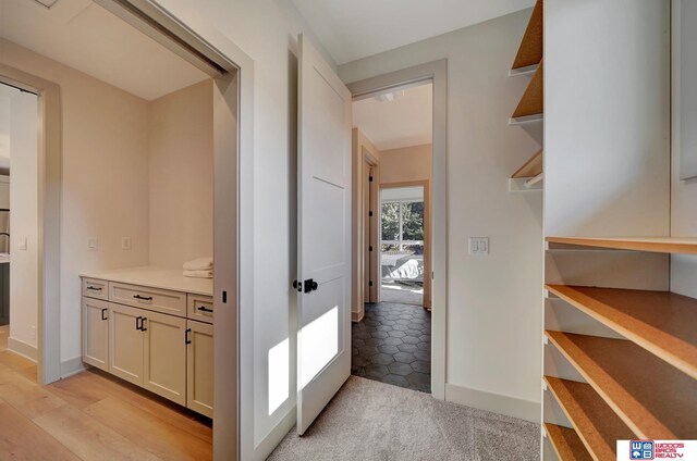 corridor featuring light colored carpet and baseboards