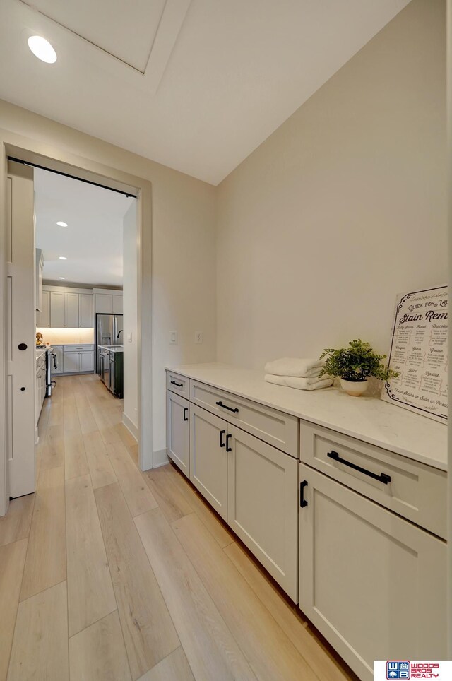 corridor featuring light wood finished floors and recessed lighting