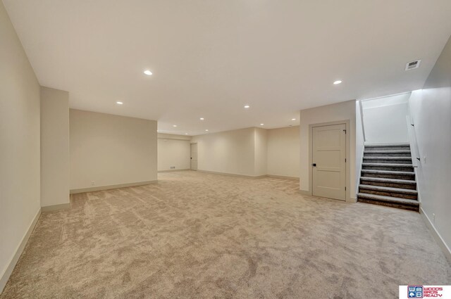 finished below grade area featuring stairway, recessed lighting, visible vents, and light colored carpet