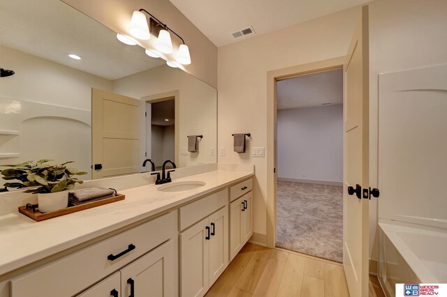 bathroom featuring baseboards, visible vents, a bathing tub, wood finished floors, and vanity