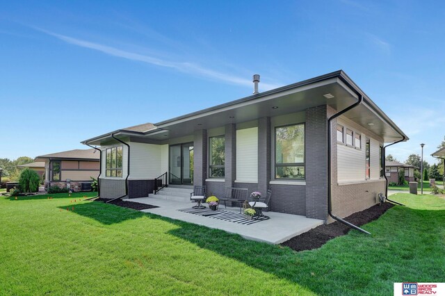 back of property featuring a patio, brick siding, and a lawn