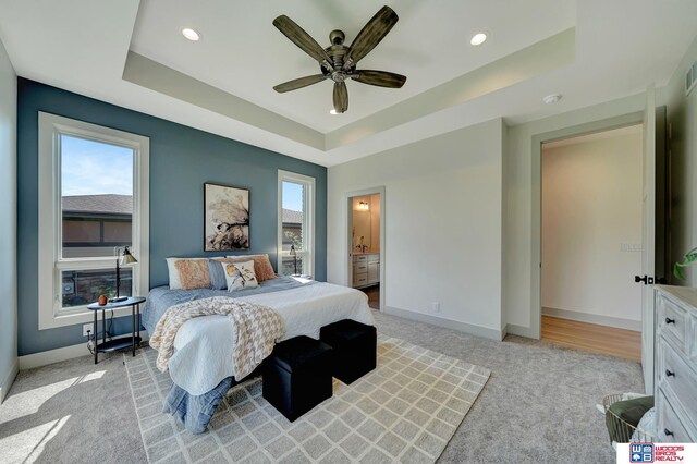 bedroom featuring light carpet, recessed lighting, a raised ceiling, and baseboards