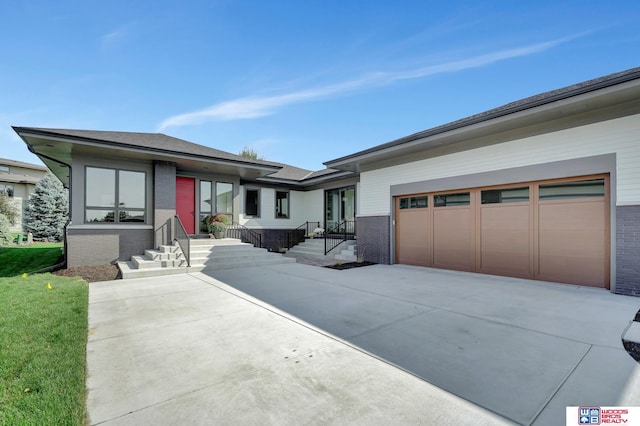 prairie-style house with a garage, concrete driveway, and brick siding