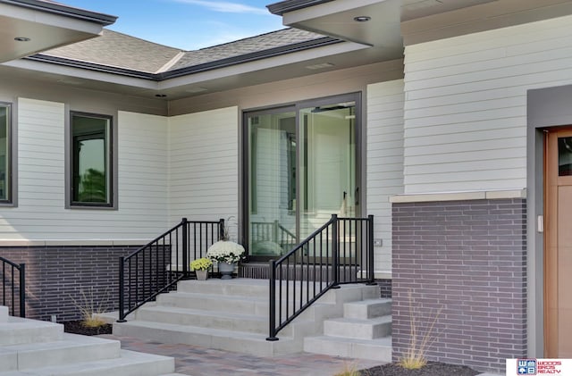 entrance to property with brick siding and roof with shingles