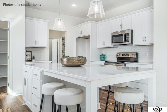 kitchen featuring stainless steel appliances, a center island, white cabinets, and a kitchen bar