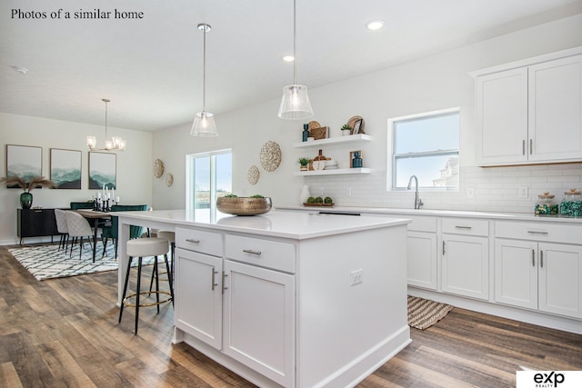 kitchen featuring a kitchen island, dark hardwood / wood-style floors, pendant lighting, white cabinetry, and backsplash