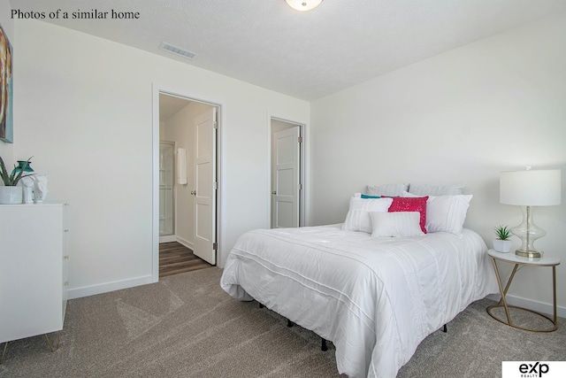 carpeted bedroom featuring ensuite bathroom and a textured ceiling