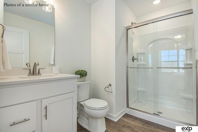 bathroom featuring wood-type flooring, vanity, an enclosed shower, and toilet