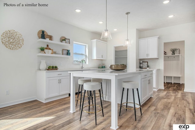 kitchen with a center island, light wood-type flooring, a breakfast bar area, and white cabinets