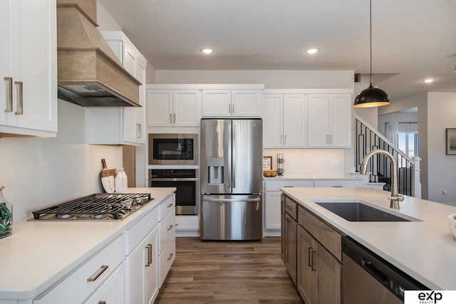 kitchen featuring sink, hanging light fixtures, stainless steel appliances, white cabinets, and custom exhaust hood