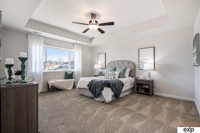 bedroom with ceiling fan, carpet flooring, and a tray ceiling