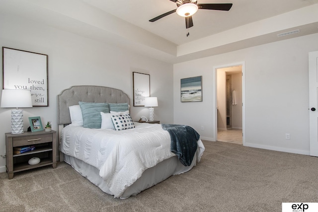 bedroom with light colored carpet, a raised ceiling, and ceiling fan