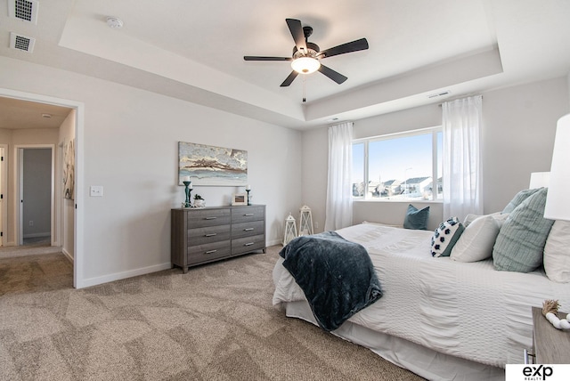 carpeted bedroom with ceiling fan and a tray ceiling