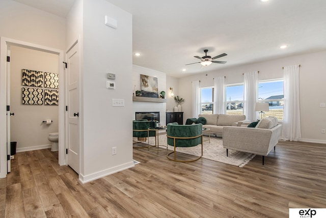 living room featuring a fireplace, light hardwood / wood-style flooring, and ceiling fan