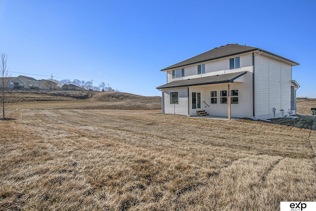 back of property featuring a patio area and a lawn