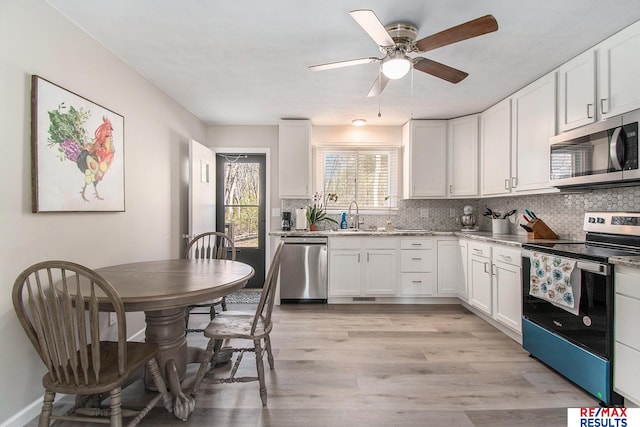 kitchen with stainless steel appliances, white cabinetry, sink, and decorative backsplash