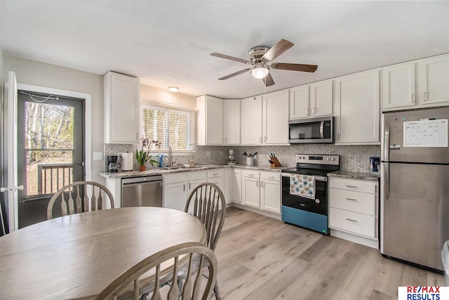 kitchen featuring white cabinetry, stainless steel appliances, light hardwood / wood-style floors, and tasteful backsplash