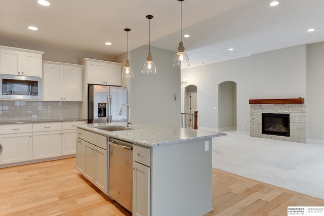 kitchen with appliances with stainless steel finishes, sink, a center island with sink, and white cabinets