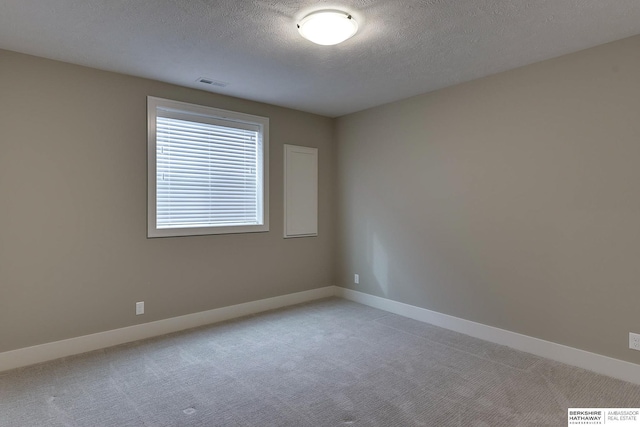 spare room featuring a textured ceiling and carpet