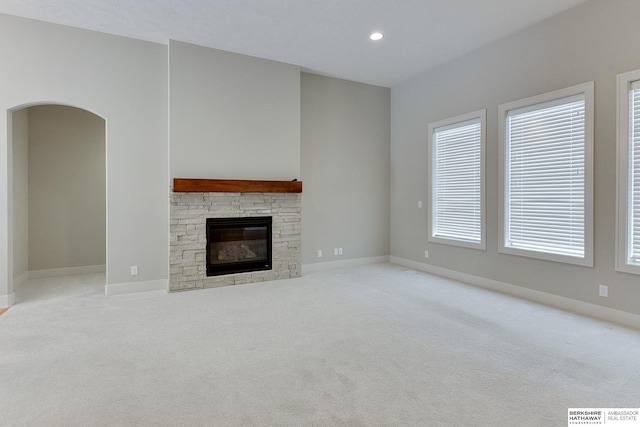 unfurnished living room featuring a healthy amount of sunlight, a fireplace, and light carpet