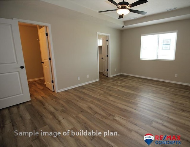 unfurnished bedroom featuring baseboards, wood finished floors, visible vents, and a walk in closet