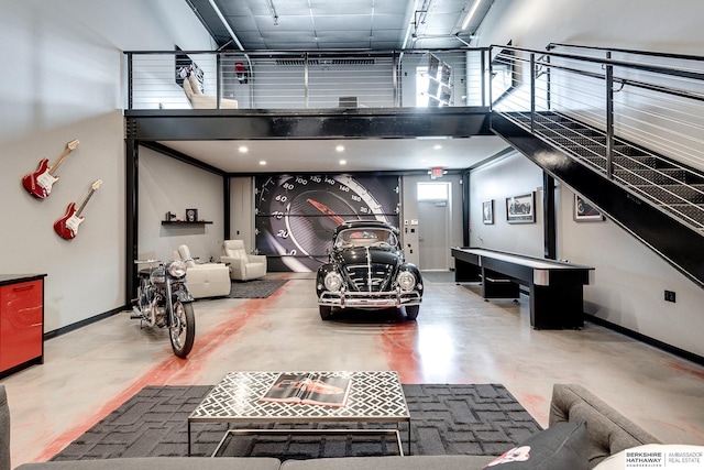 recreation room with concrete flooring and a high ceiling