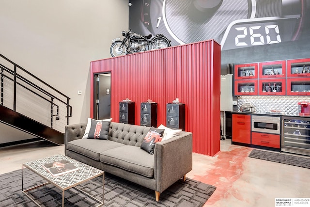 living room featuring concrete floors, beverage cooler, and a high ceiling