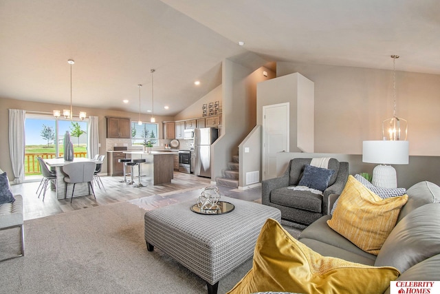 living room featuring high vaulted ceiling, light wood-type flooring, and a notable chandelier