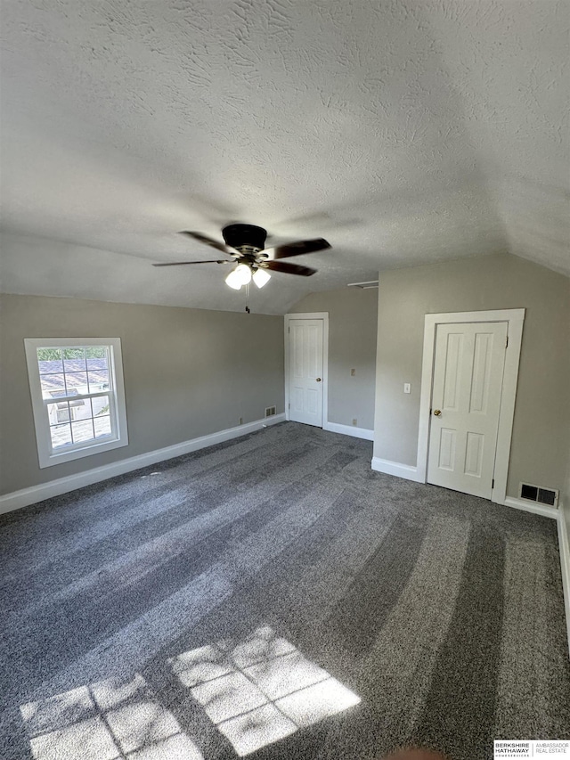 empty room featuring lofted ceiling, carpet floors, a textured ceiling, and ceiling fan